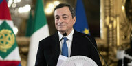 Mario Draghi steht am Rednerpult, hinter ihm Fahnen und gold-verzierte Spiegel