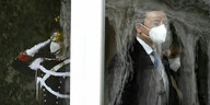 Mario Draghi mit Gesichtsmaske, eingerahmt von einem Fenster, geht an einer Wache vorbei