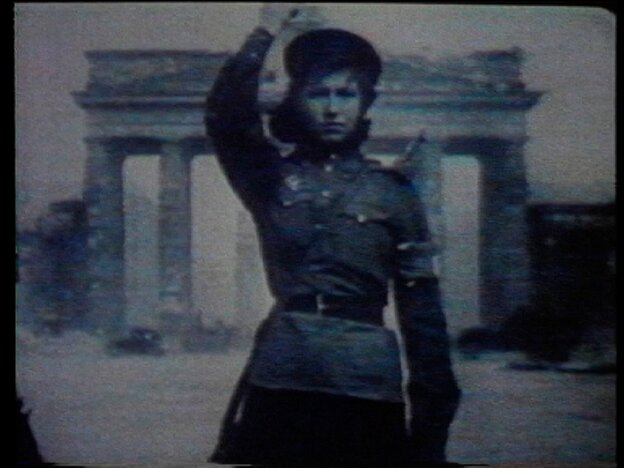 Schmalspurfilmbild, eine Soldatin grüßt, im Hintergrund das Brandenburger Tor in Berlin