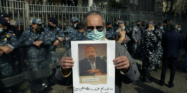 Ein Demonstrant hält ein Portrait von Lokman Slim in den Händen