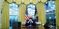 US Präsident Joe Biden sitzt mit Mund-Nasenschutz am Schreibtisch im Oval Office
