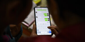 Zwei Personen schauen auf ein Smartphone auf dem die chiesische App Wechat geöffnet ist