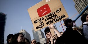 Protestierende halten ein Pappschild mit dem Youtube-Logo und der Aufschrift "Dieses Video ist in der EU nicht verfügbar"