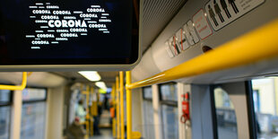 eine wenig besetzte Straßenbahn, in einem Display steht das Wort Corona