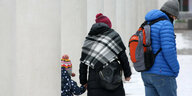 Mann, Frau und Kind machen warm angezogen einen Winterspaziergang
