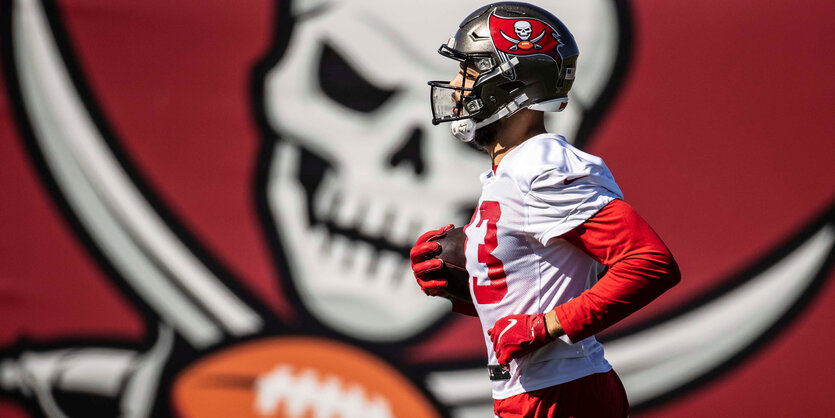 Ein Football-pieler trainiert vor dem Piratenlogo der Tampa Bay Buccaneers