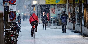 Ein Radfahrer fährt über einen zugeschneiten Radweg.