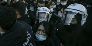 Polizistinnen mit Helmen nehmen eine Studentin am Rande einer Demonstration fest