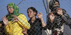 Flüchtlinge stehen hinter einem Zaun