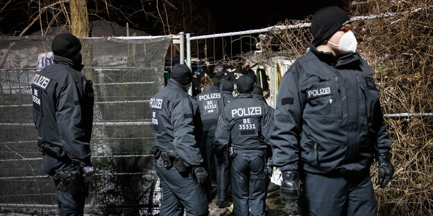 Mehrere Berliner Polizisten drängen durch ein Abspeergitter in das Obdachlosencamp an der Rummelsburger Bucht – das Camp wird am Samstag, dem 6.2.21 geräumt