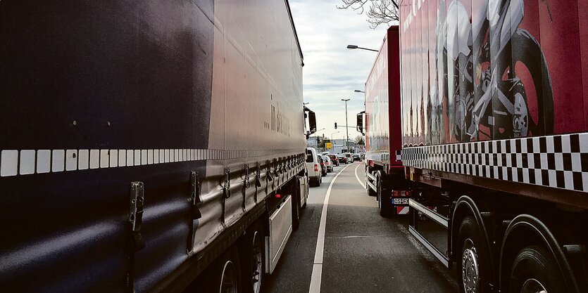 LKWs und PKWs auf einer dicht befahrenen Straße.