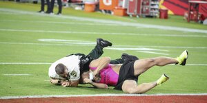 Ein Flitzer wird vom Sicherheitsdienst auf dem Football-Spielfeld zu fall gebracht - der Mann trägt einen pinken Mankini und darüber eine schwarze Short