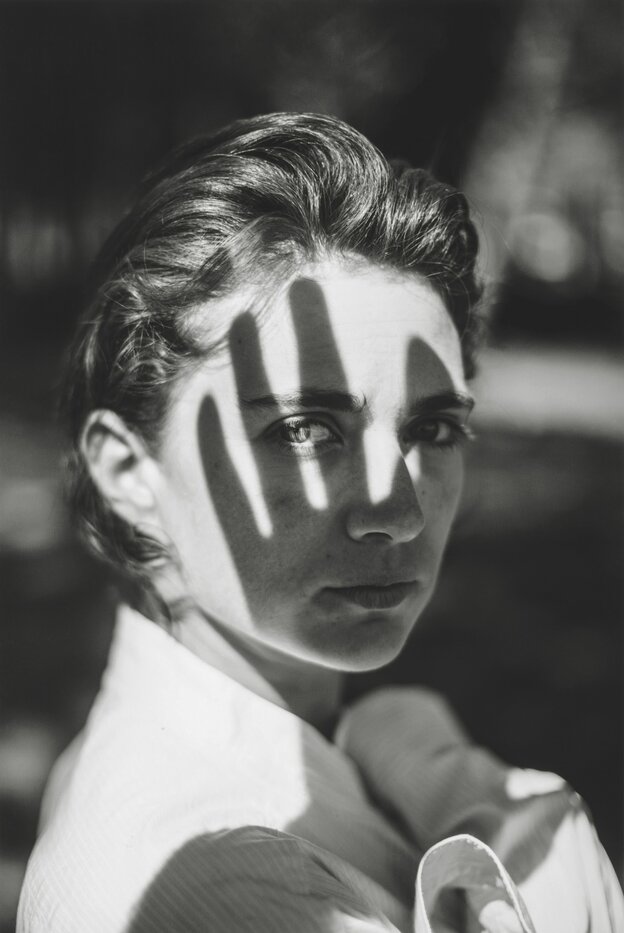 Schwarzweißes Foto, der Schatten einer Hand über dem Gesicht einer Frau