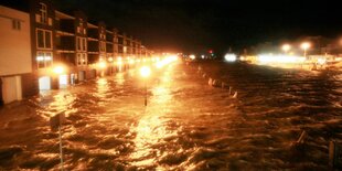 Wassermassen rauschen über eine Straße bei Nacht