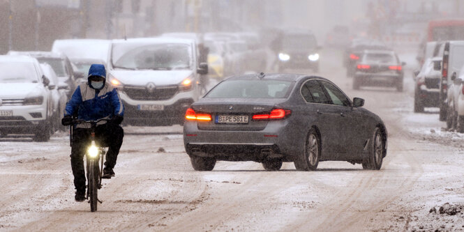 Winter in Berlin: Ein Fahrer eines Lieferservice fährt mit einem Fahrrad auf der verschneiten Luisenstraße.