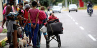 Geflüchtete aus Venezuela auf einer Straße - eine famile mit Hund und Kinderwagen