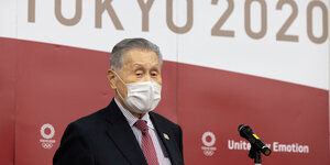 Yoshiro Mori mit Maske vor einer Werbewand, auf der "Tokyo 2020" steht