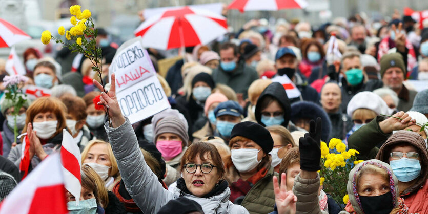 DemonstrantInnen mit rotweißen Flaggen und Regenschirmen