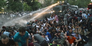 In Jerewan schießt ein Wasserwerfer auf sitzende Menschen.