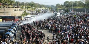 Von Polizeifahrzeugen aus werden Wasserwerfer gegen Demonstranten eingesetzt