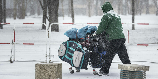 Ein Obdachloser mit einem Einkaufswagen, aufgenommen waehrend starken Schneefalls in Berlin