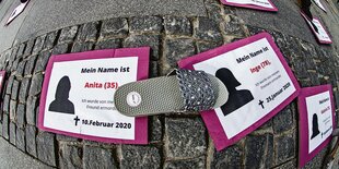 Schilder mit Totenanzeigen von Frauen liegen auf einer Straße.