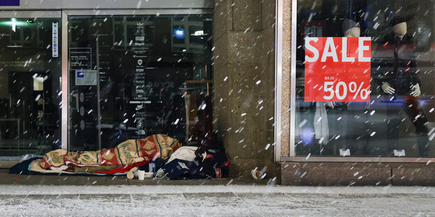 Ein obdachloser Mensch schläft am frühen Morgen im Eingang eines Kaufhauses in der Hamburger Innenstadt.