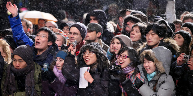 Menschen im Schneegestöber, die einem Filmstar außerhalb des Bildes zujubeln