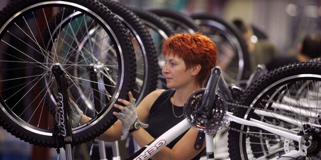 Eine Mitarbeiterin in der Fahrradproduktion mit vielen Fahrrädern