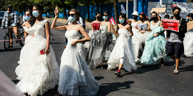 mehrere junge Frauen in Brautkleidern protestieren gegen die Militärdiktatur. Manche recken als Zeichen des Protestes drei Finger in die Höhe