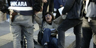 Eine junge Frau wird von Sicherheitskräften über den Bordstein geschleift