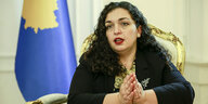 Die Politikerin Vjosa Osmani sitzt vor der Fahne des Kosovo und spricht