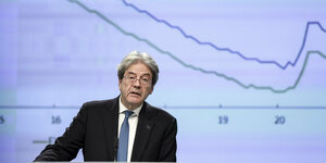 Portrait EU-Wirtschaftskommissar Paolo Gentiloni vor Konjunkturkurve