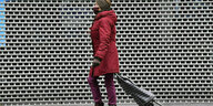 Eine Frau mit Einkaufstrolley geht an einem geschlossenen Geschäft vorbei