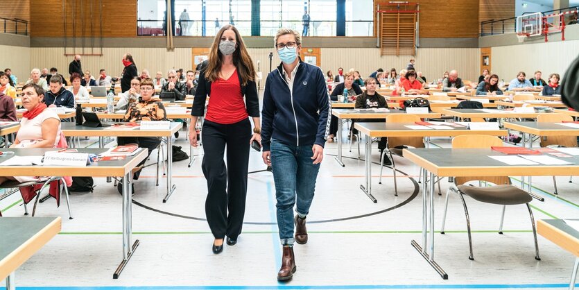 Die beiden Kandidaten laufen in einem Saal zur Bühne, Wissler in rotem T-Shirt, Hennig-Welsow in Jeans und Sportjacke