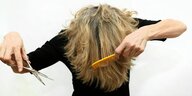 Eine Frau versucht sich selbst die Haare zu schneiden