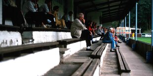 Fans sitzen auf einer baufälligen Tribüne