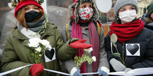 Frauen in Russland halten gemeinsam ein Band. Sie tragen Rosen in den Händen und Herzen