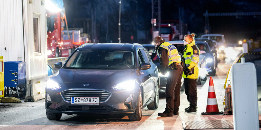 Ein Polizist und eine Polizistin in Warnwesten stehen vor einer Schlange Autos