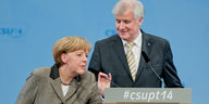 Seehofer steht am Rednerpult und Merkel dreht das Mikro um zu sprechen