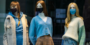 drei Schaufensterpuppen mit Gesichtsmaske in Winterkleidung