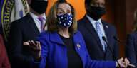Nancy Peslosi in blauem Jackett spricht mit Mundschutz