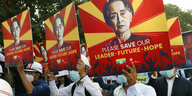 Demonstrierende halten Poster mit Aung San Suu Kyi Aufdruck und der Aufschrift "Please save our leader future hope"