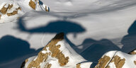 Berge im Schnee, der Schatten eines Hubschraubers