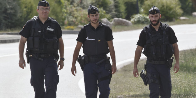 Drei Polizisten laufen eine Straße entlang