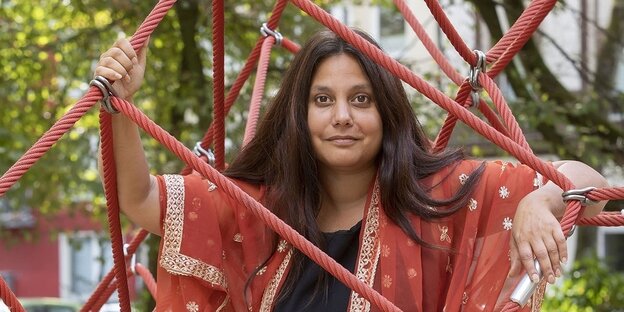Die Autorin Mithu Sanyal steht in einem Klettergerüst für Kinder