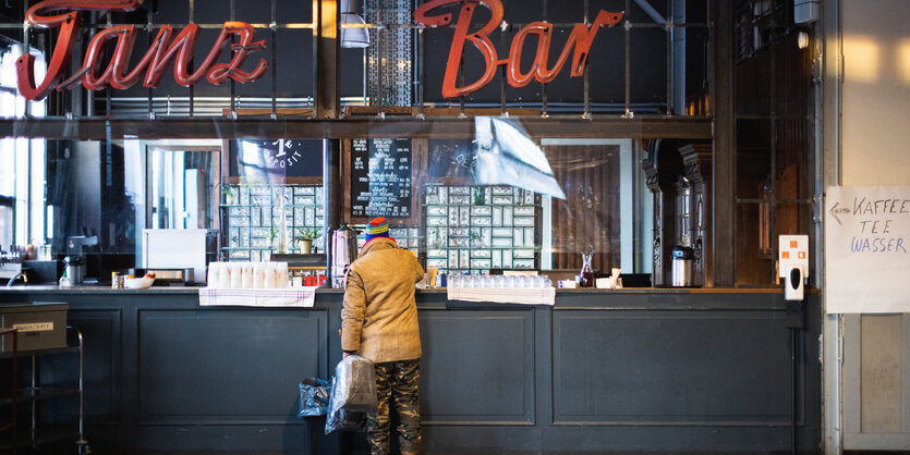 Rückansicht eines Mannes, der an einer Bar steht.