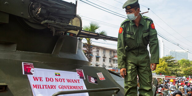 Ein Soldat schauf auf einen Anti-Diktatur-Spruch auf seinem Panzer in Myanmar. Daruf steht: "Wir wollen keine Militärregierung"