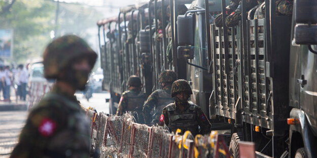 Soldat steht vo geparkten Truppentransporterrs des Militärs
