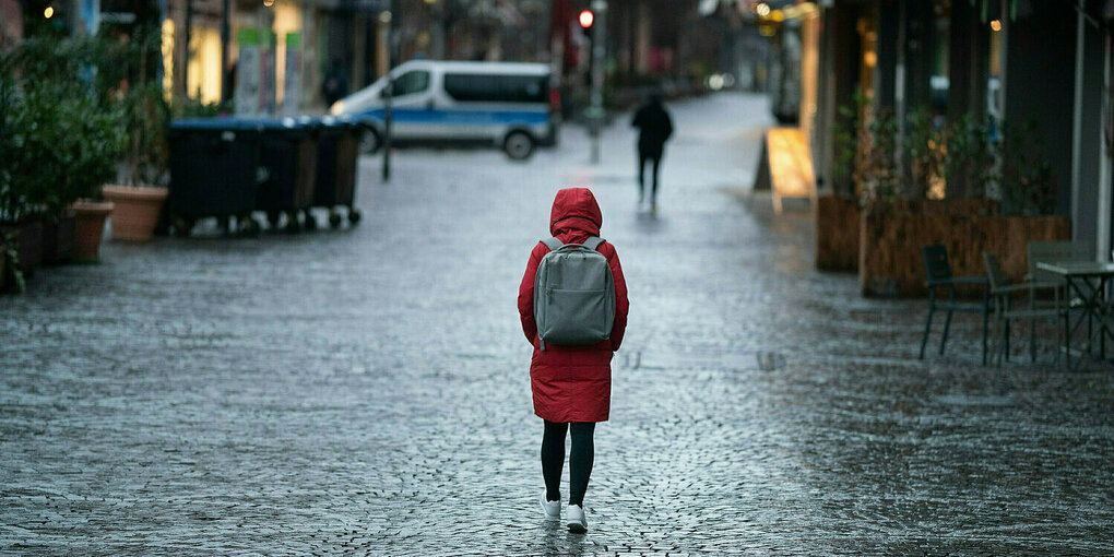 Eine Frau läuft durch eine Fussgängerzone im Regen